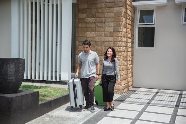 Feliz pareja llevando su maleta