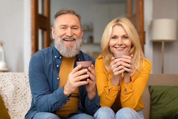 Feliz pareja madura bebiendo café disfrutando de momentos juntos en casa