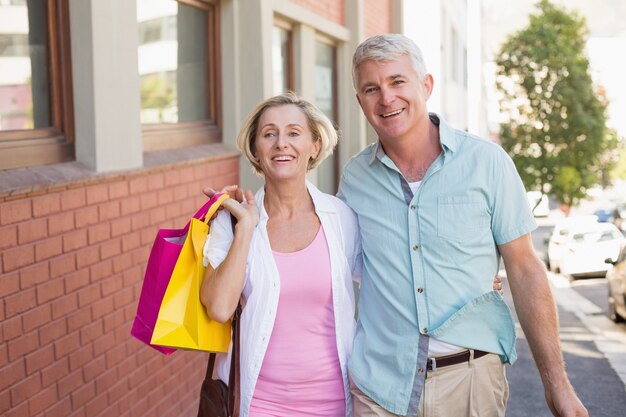 Feliz pareja madura caminando con sus compras de compras