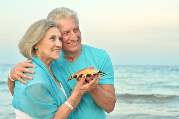 Feliz pareja madura disfrutar del aire fresco en la playa con concha