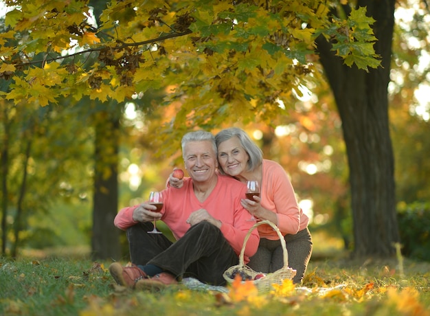 Feliz pareja madura haciendo un picnic en el parque en otoño