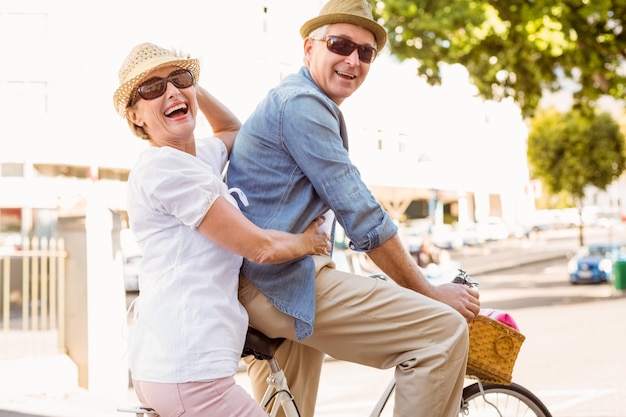 Feliz pareja madura ir a dar un paseo en bicicleta por la ciudad