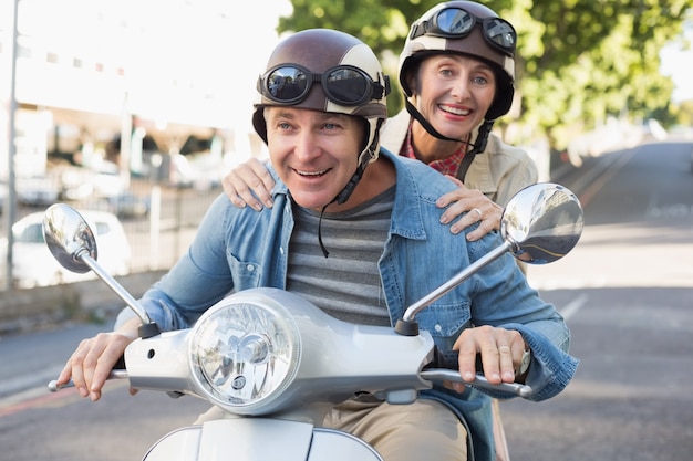 Foto feliz pareja madura montando un scooter en la ciudad