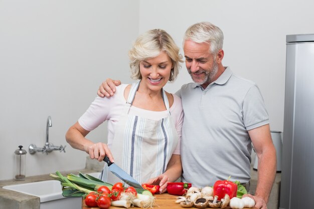 Feliz pareja madura preparando comida juntos en la cocina