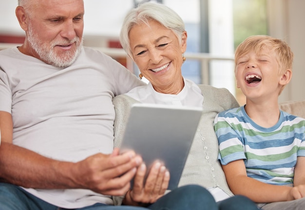 Una feliz pareja madura que se une a su nieto mientras cuida niños y usa una tableta digital para hacer videollamadas en casa Los abuelos se relajan con su lindo nietecito y navegan