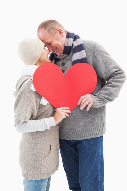 Feliz pareja madura en ropa de invierno con corazón rojo