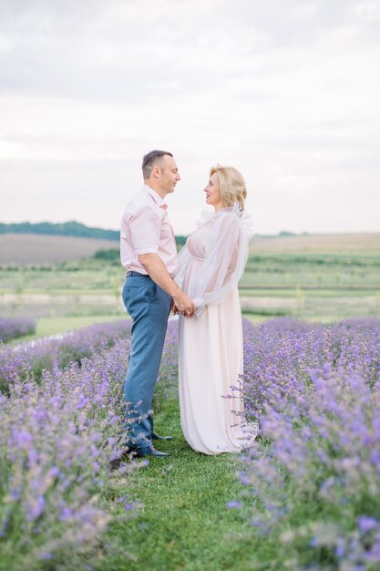 Feliz pareja de mediana edad en un campo de lavanda púrpura
