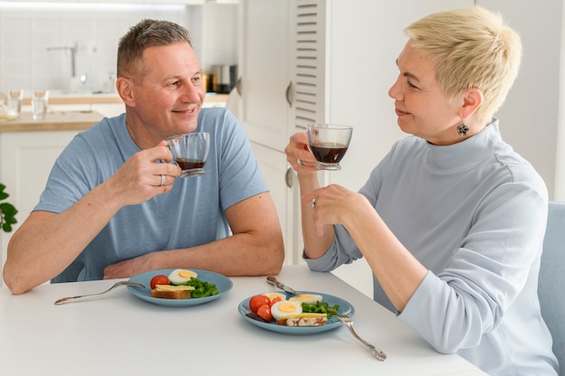 Feliz pareja de mediana edad disfruta comiendo un desayuno saludable juntos mirándose