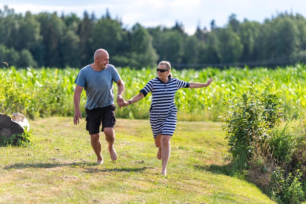 Feliz pareja de mediana edad tomados de la mano corriendo en el jardín el concepto de una relación feliz