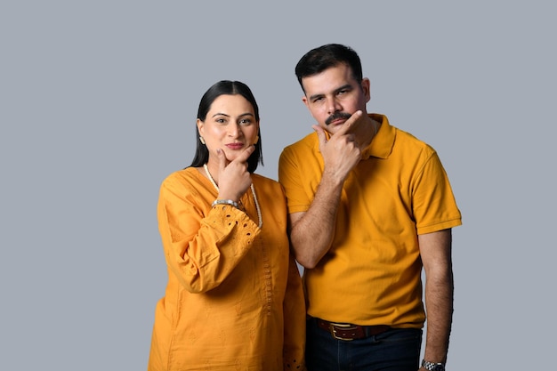 Feliz pareja mirando enfrente contra la pared gris modelo paquistaní indio