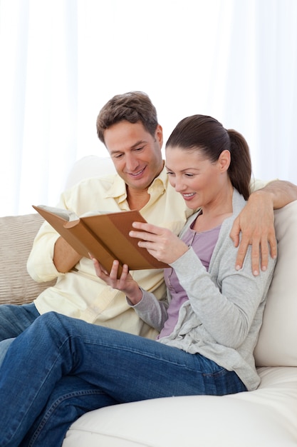 Feliz pareja mirando fotos en un álbum de fotos mientras se relaja