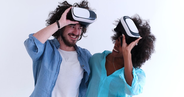 Feliz pareja multiétnica obteniendo experiencia usando gafas VR de realidad virtual, aisladas en fondo blanco