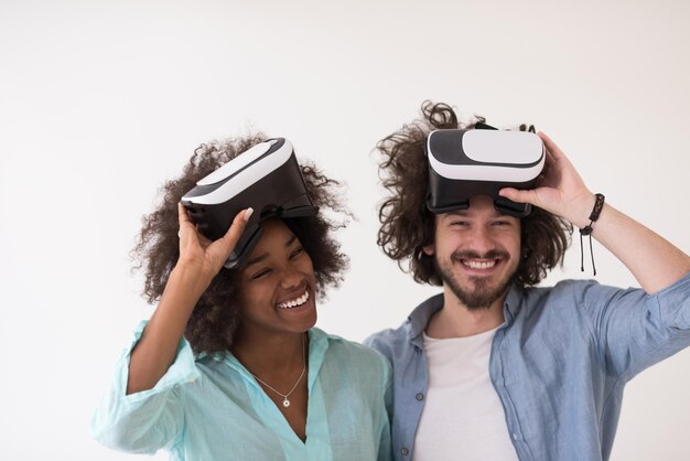 Feliz pareja multiétnica obteniendo experiencia usando gafas VR de realidad virtual, aisladas en fondo blanco