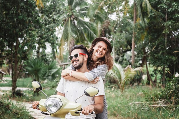 Feliz pareja multinacional viajando en moto en la selva, luna de miel, vacaciones,