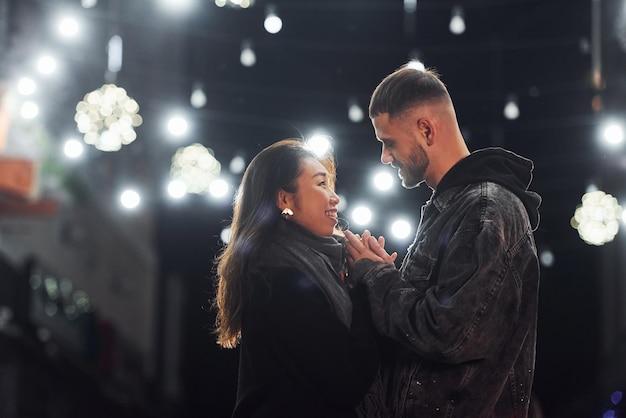 Feliz pareja multirracial juntos al aire libre en la ciudad celebrando el Año Nuevo