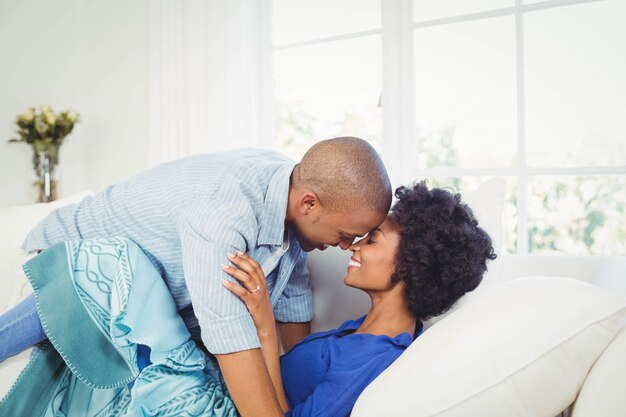 Feliz pareja nariz a nariz en el sofá de casa