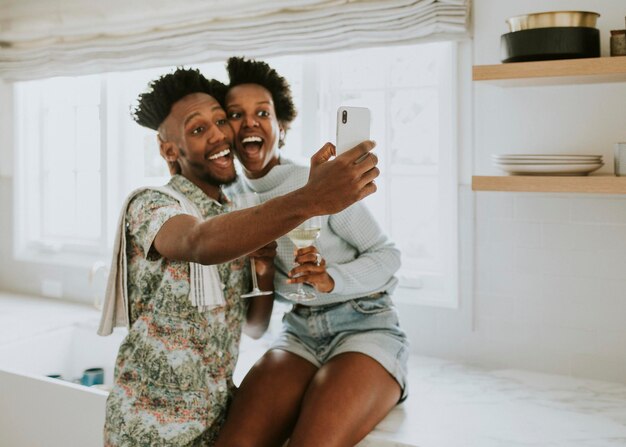 Feliz pareja negra tomando un selfie en casa con un móvil