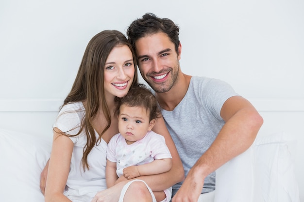 Feliz pareja con niña en la cama