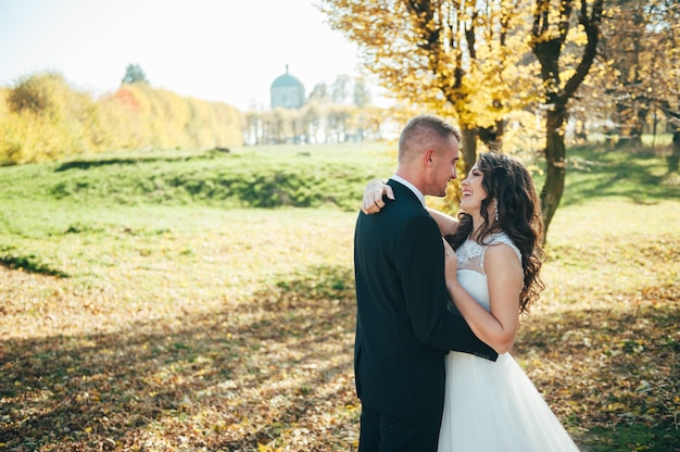 Feliz pareja de novias caminando en el parque otoño