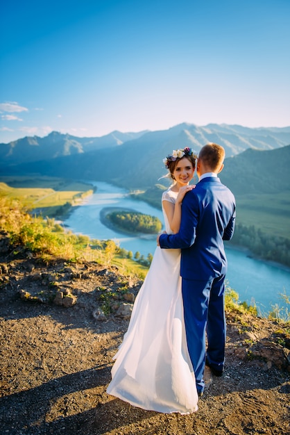 Feliz pareja de novios sobre el hermoso paisaje con montañas