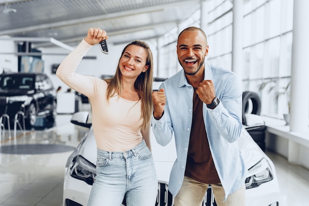 Foto feliz pareja o familia emocionada comprando un coche nuevo y mostrando las llaves