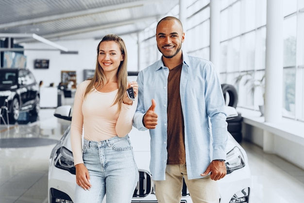 Feliz pareja o familia emocionada comprando un coche nuevo y mostrando las llaves