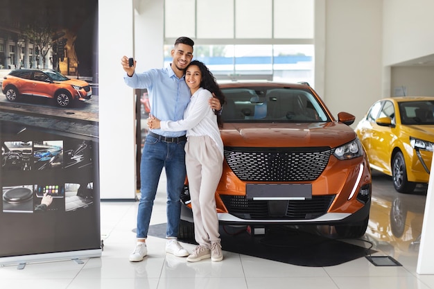 Feliz pareja de Oriente Medio mostrando clave comprando auto nuevo