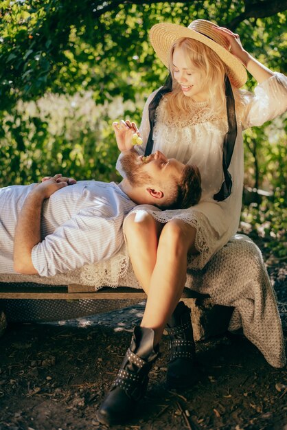 Feliz pareja pasar tiempo juntos y alimentarse con uvas en verano en un día soleado