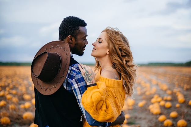 Feliz pareja de pie en campo de calabaza