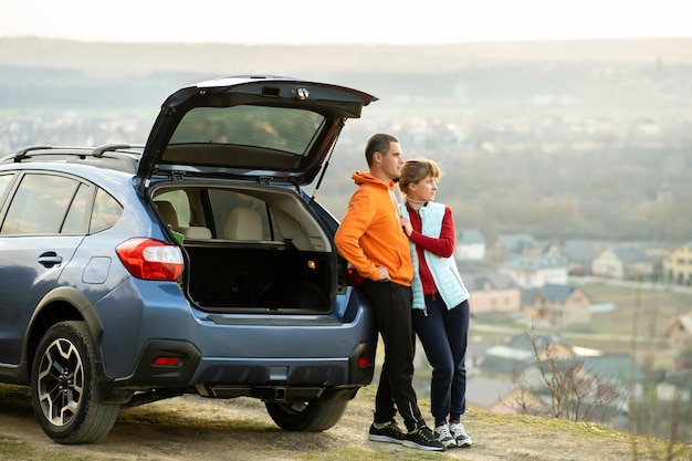 Feliz pareja de pie juntos cerca de un automóvil