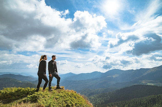 La feliz pareja de pie en la montaña con un pintoresco celaje