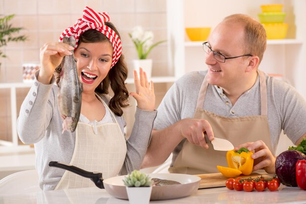 Feliz pareja preparando comida en la cocina