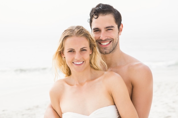 Feliz, pareja que se abraza, en la playa