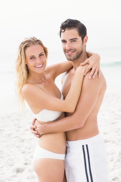 Feliz, pareja que se abraza, en la playa