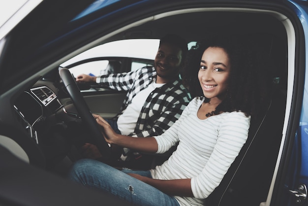 Feliz pareja de raza mixta en asientos de coche Prueba de manejo