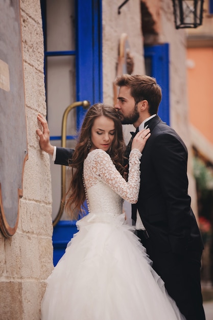 Feliz pareja de recién casados abrazándose y besándose en la vieja calle de la ciudad europea