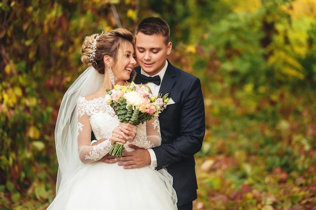 Feliz pareja de recién casados La novia sonríe cuando el novio la abraza