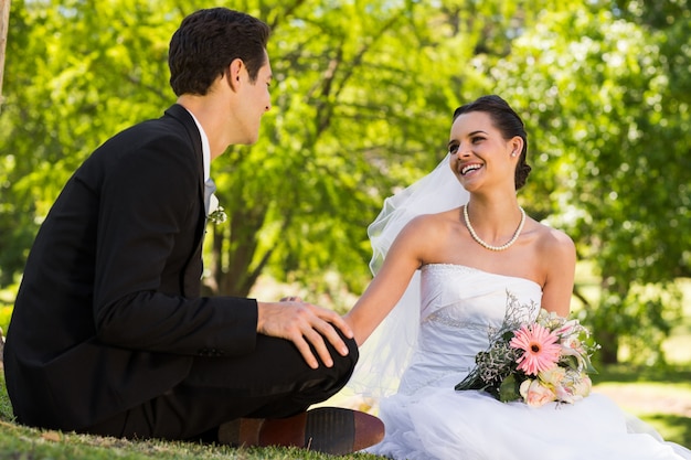 Feliz pareja de recién casados ​​sentados en el parque