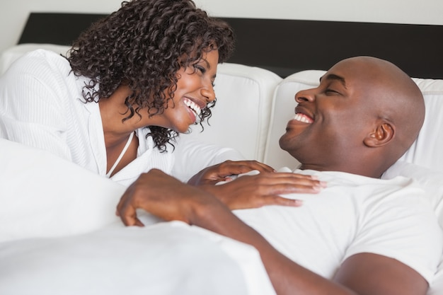 Feliz pareja riendo juntos en la cama