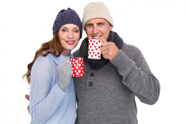 Feliz pareja en ropa de abrigo con tazas