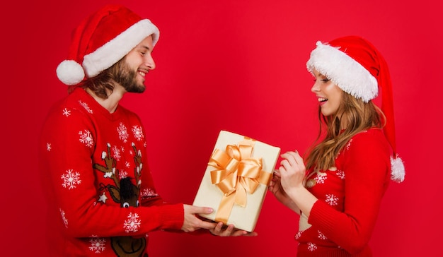 Feliz pareja de santa en suéter rojo sombrero de navidad con caja presente celebración de feliz año nuevo