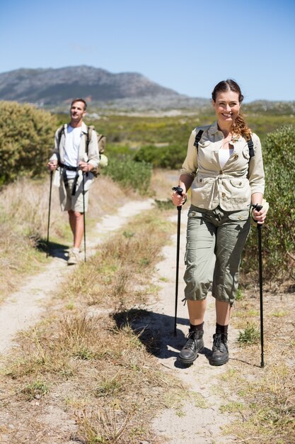 Feliz pareja de senderismo caminando por sendero en un día soleado