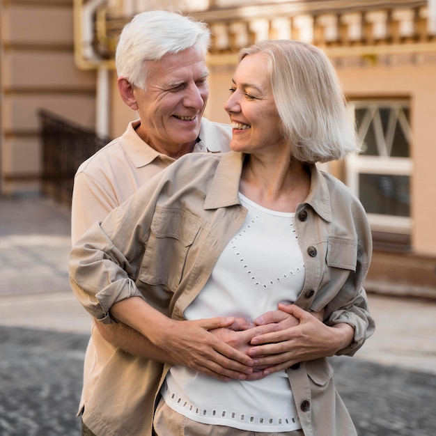 Feliz pareja senior abrazados románticamente en la ciudad