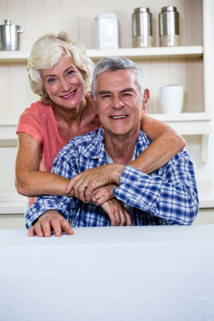 Feliz pareja senior abrazando en cocina en casa