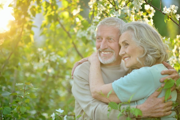 Feliz pareja senior abrazándose sobre fondo de flores