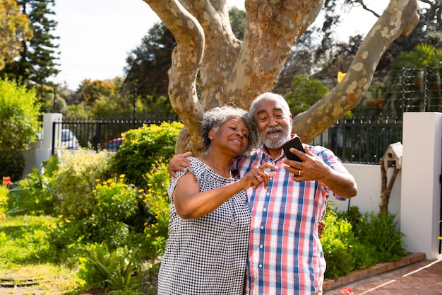 Feliz pareja senior afroamericana tomando selfie en el jardín. estilo de vida de jubilación activa en el hogar y el jardín.