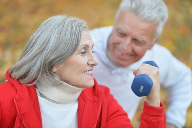 Feliz pareja senior de ajuste haciendo ejercicio en el parque otoño