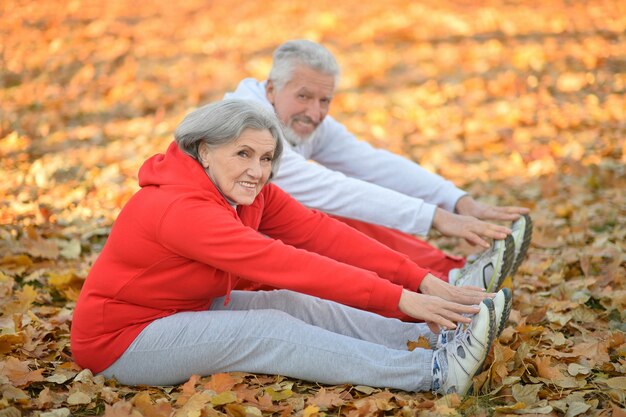 Feliz pareja senior de ajuste haciendo ejercicio en el parque otoño