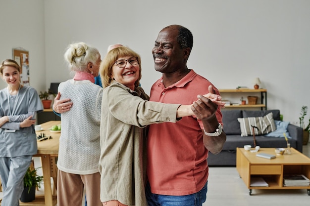 Feliz pareja senior aprendiendo a bailar durante la lección en el hogar de ancianos