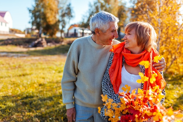 Feliz pareja senior caminando en el bosque de otoño